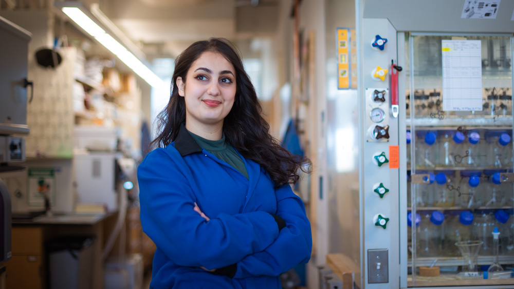 Photo of Azin Saebi in lab with blue lab coat