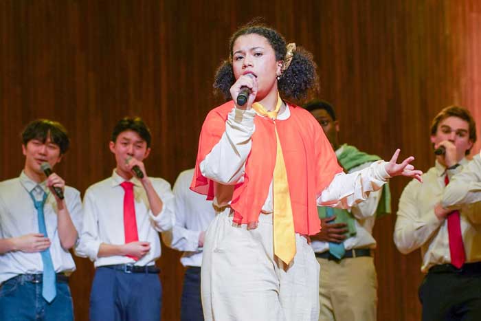 The Logarhythms perform while wearing ties, with female singer in foreground