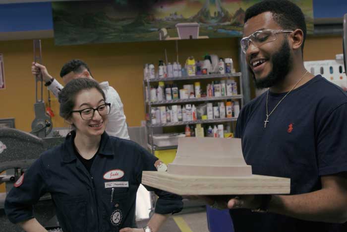 2 students discuss an object in a lab